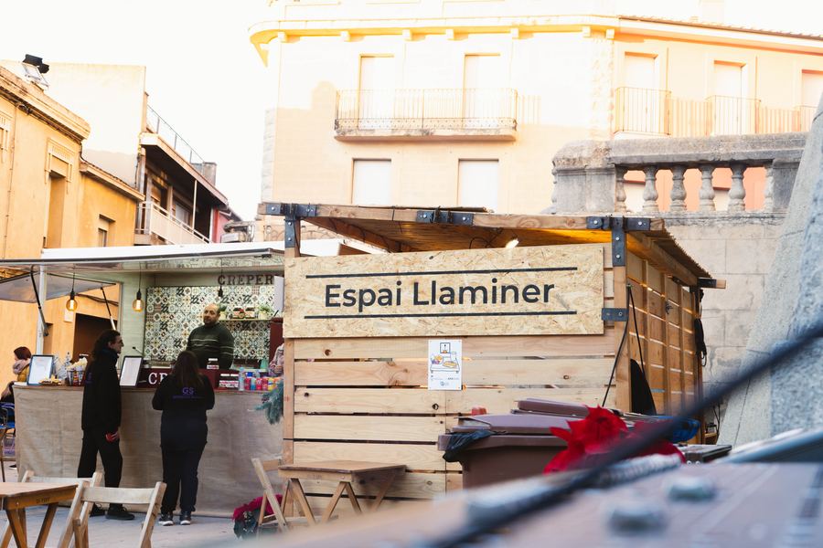 Estand de fusta retolat «Espai Llaminer» al carrer d’una fira