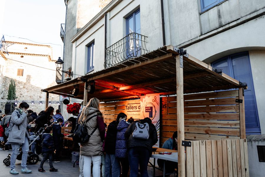 Cua de gent davant d’un estand de tallers en una fira